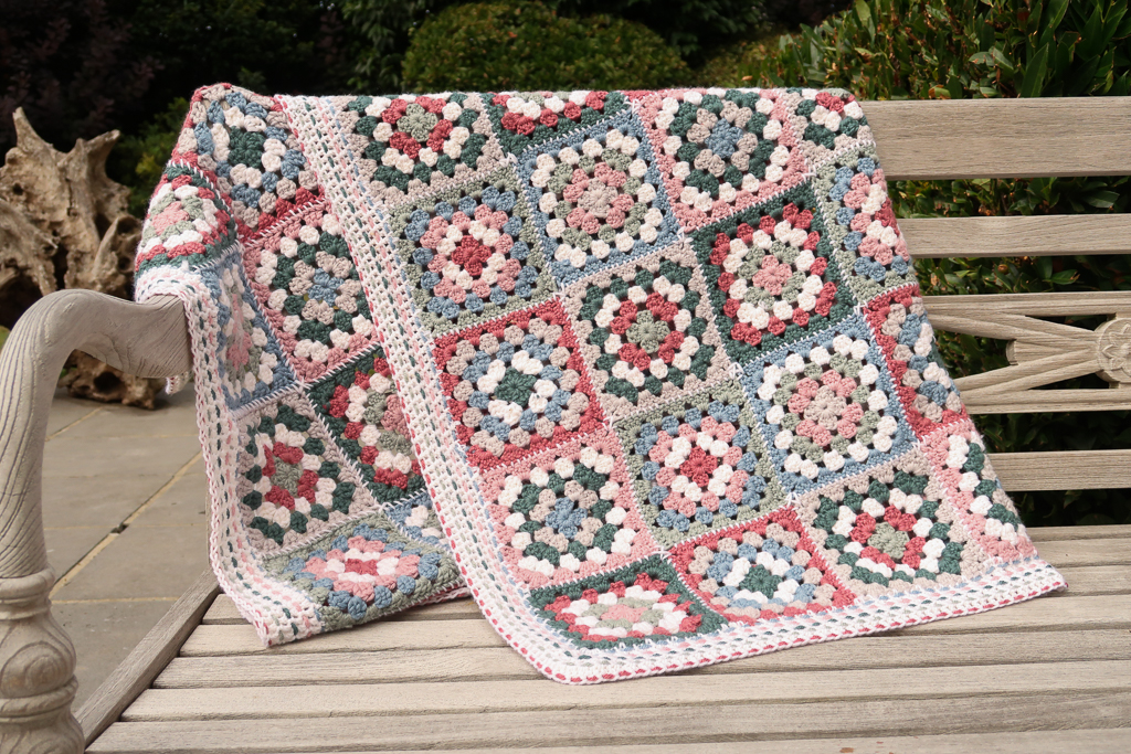 complete view of the granny square blanket on a bench