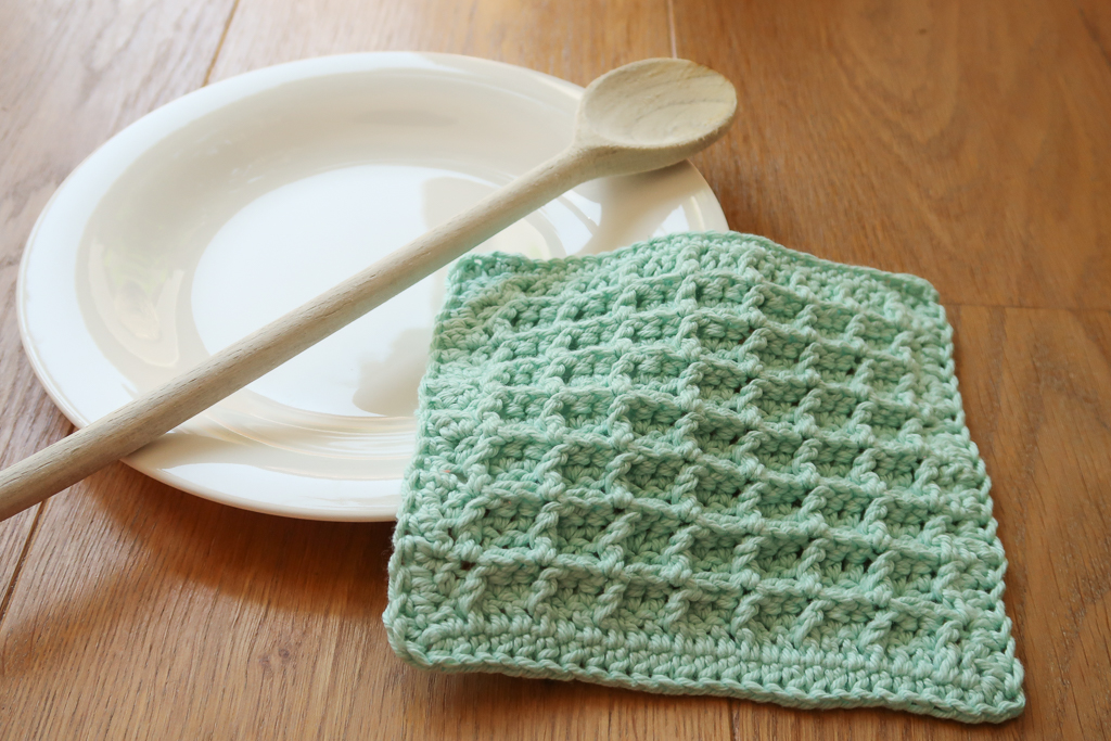 waffle crochet dishcloth pattern on a plate with wooden spoon