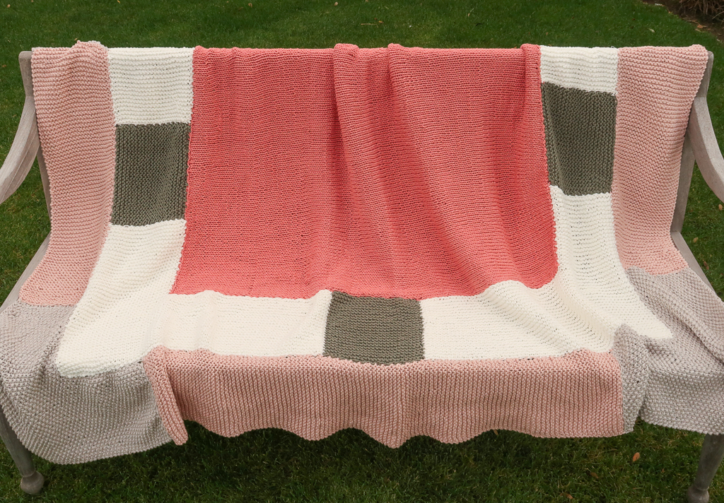 dovetail beginner knitting blanket pattern shown on a bench