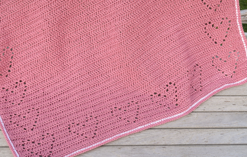 crochet baby blanket laid on a bench