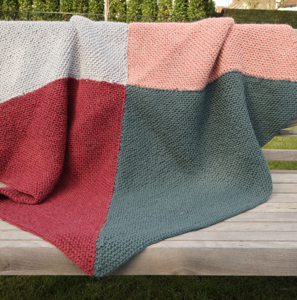 quadrant baby blanket with chunky yarn laid out over a bench