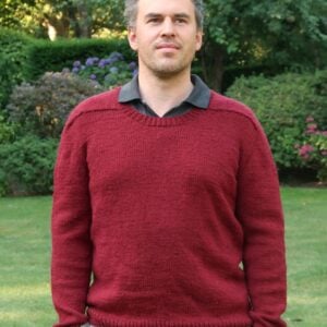 Man wearing the finished Out and About sweater made from this knitting pattern for mens sweater in dark red DK yarn