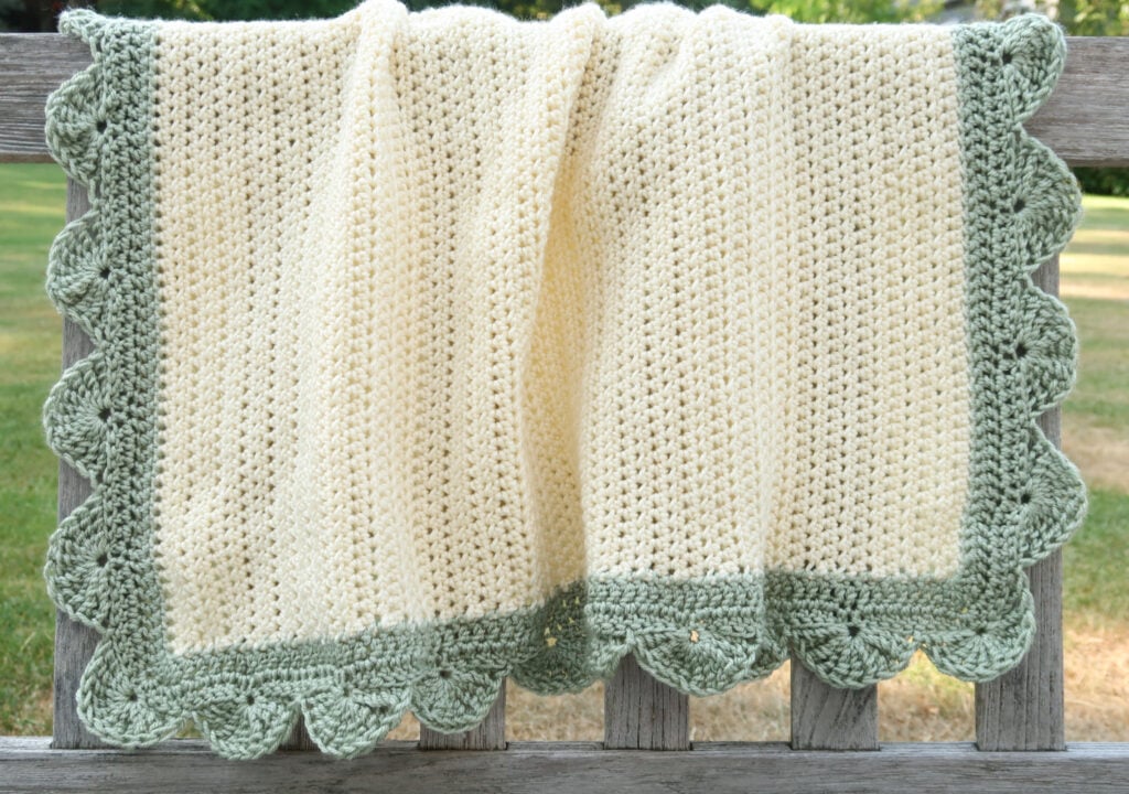 Full view of the easy baby blanket crochet pattern free draped on a bench