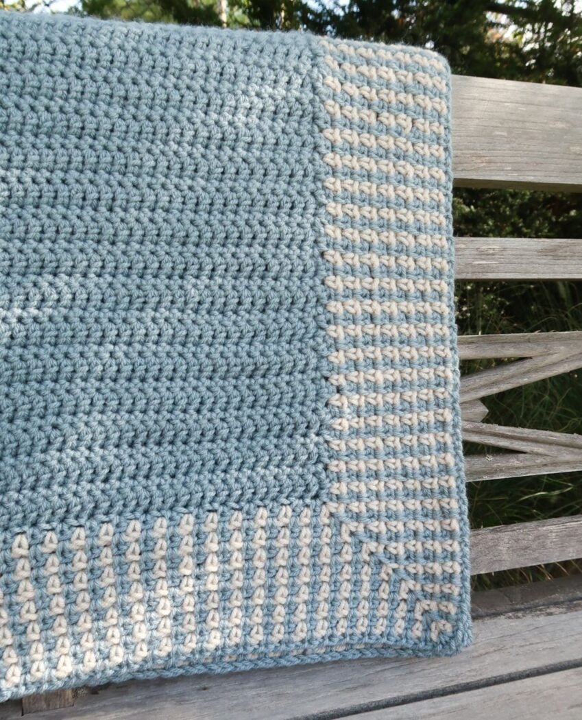 Close up of a crochet border for baby blanket showing the moss stitch texture in two colors