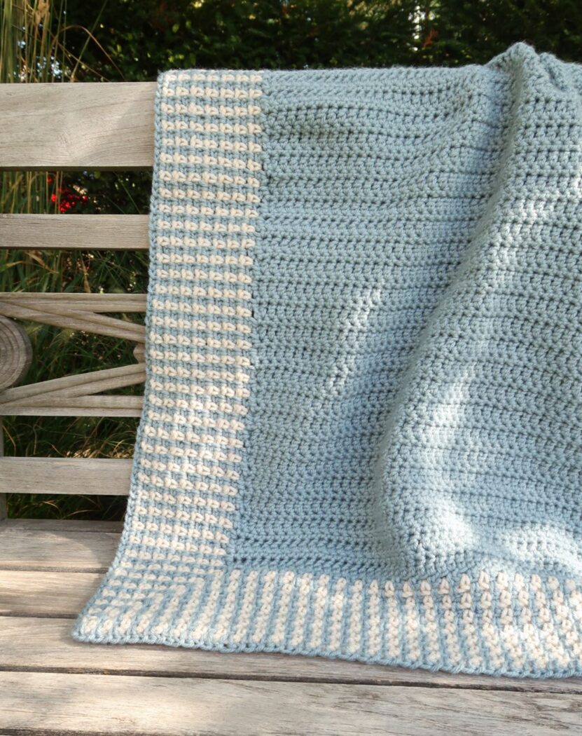 Crochet baby blanket pattern draped flat, showing the full moss stitch border